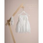 Βαπτιστικό φόρεμα Piccolino Elisa Ivory. Φόρεμα με ιδιάιτερο ύφασμα με σχέδιο στο μπούστο, δαντέλα ζωνάκι στη μέση και ασσύμετρη τούλινη φούστα . Στο φόρεμα ξεχωρίζει η εντυπώσιακή πλάτη όπου ξέκινώντας από τους ώμους αυτή η εντυπωσιακή δαντέλα καταλήγει εώς πίσω χαμηλά στην μέση .Το ντεκόρ του φορέματος αποτελείται από χειροποίητο λουλούδι με μαραμπού και στρας swarovski. Το φόρεμα συνοδέυεται απο κορδέλα με ντεκόρ όμοιο με το φόρεμα