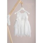 Βαπτιστικό φόρεμα Piccolino Elisa Ivory. Φόρεμα με ιδιάιτερο ύφασμα με σχέδιο στο μπούστο, δαντέλα ζωνάκι στη μέση και ασσύμετρη τούλινη φούστα . Στο φόρεμα ξεχωρίζει η εντυπώσιακή πλάτη όπου ξέκινώντας από τους ώμους αυτή η εντυπωσιακή δαντέλα καταλήγει εώς πίσω χαμηλά στην μέση .Το ντεκόρ του φορέματος αποτελείται από χειροποίητο λουλούδι με μαραμπού και στρας swarovski. Το φόρεμα συνοδέυεται απο κορδέλα με ντεκόρ όμοιο με το φόρεμα